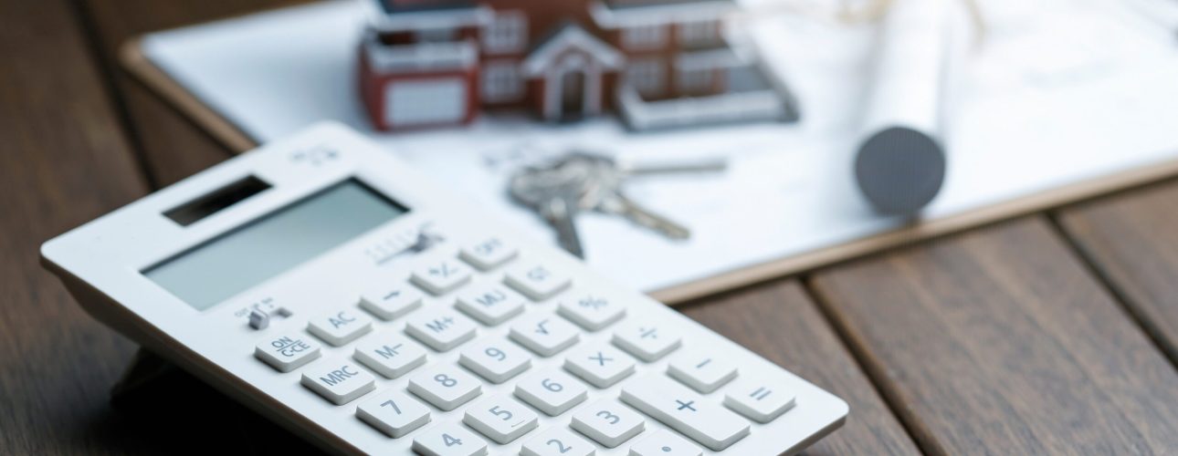 a calculator in front of a Villa house model with a blueprint