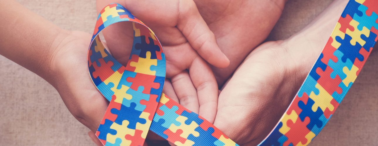 Hands holding puzzle ribbon for autism awareness